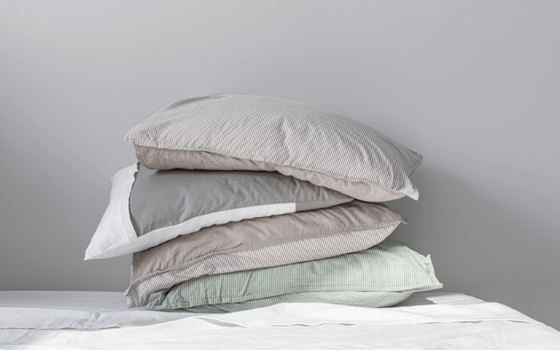An image of freshly laundered pillowcases stacked neatly on a bed.