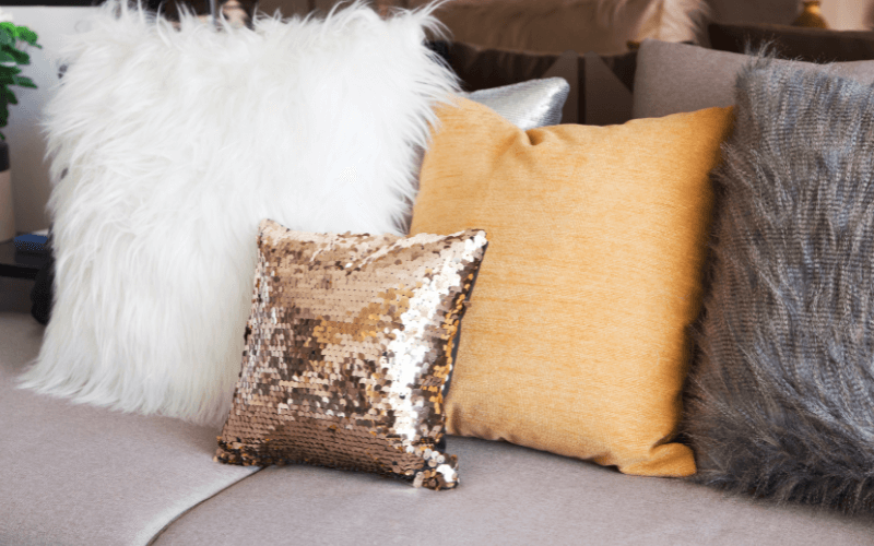 An image of layered cushions and throws on a sofa.