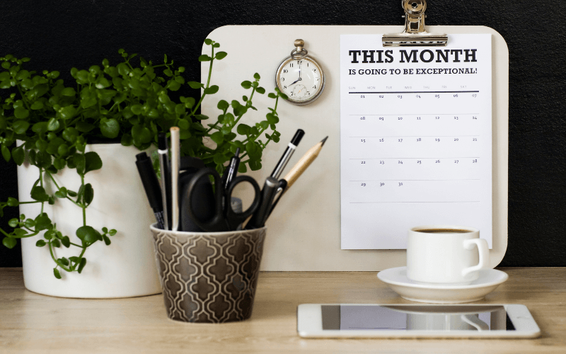 Image of a desk organiser filled with office supplies. A few pens, paper clips, a pair of scissors, etc. A cup of coffee to the side.