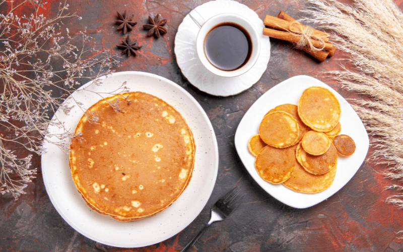 Image of a cup of coffee with a plate of pancakes.