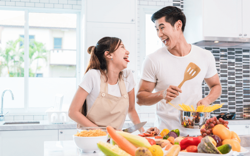 Image of a person in the kitchen preparing different ingredients with their significant other.