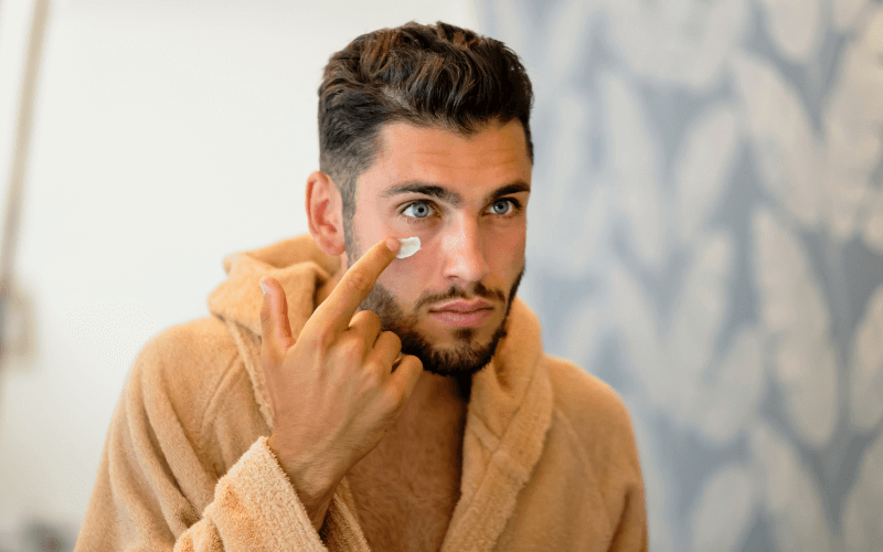 Image of a person rubbing oil, cream, or soap on their cheeks. This person is either half-naked or wearing a robepajamas.