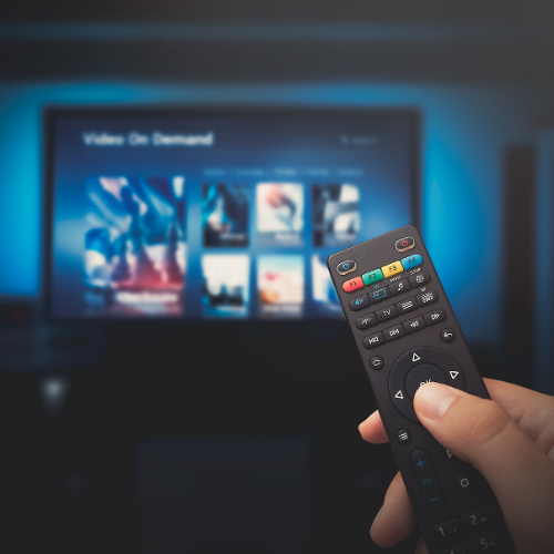 Small image of a person holding a remote towards a T.V.