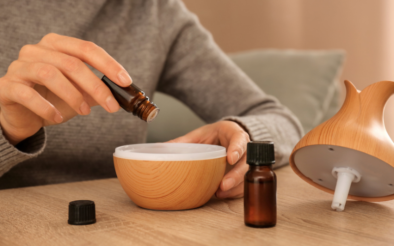 A person adding a few drops of essential oil to a diffuser