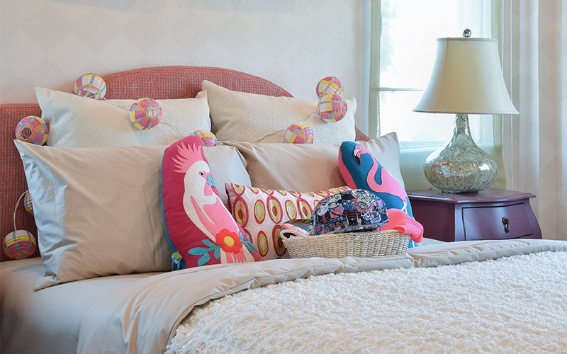 Image of a bed with different shaped-colourful pillows