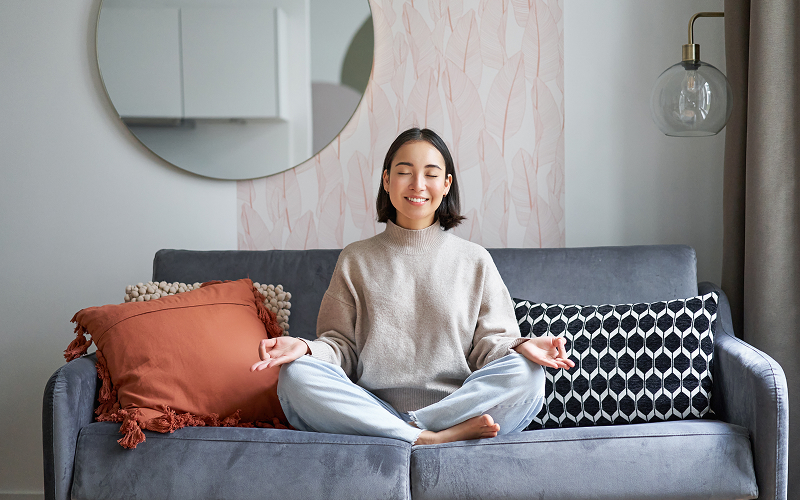 A person meditating inside her home