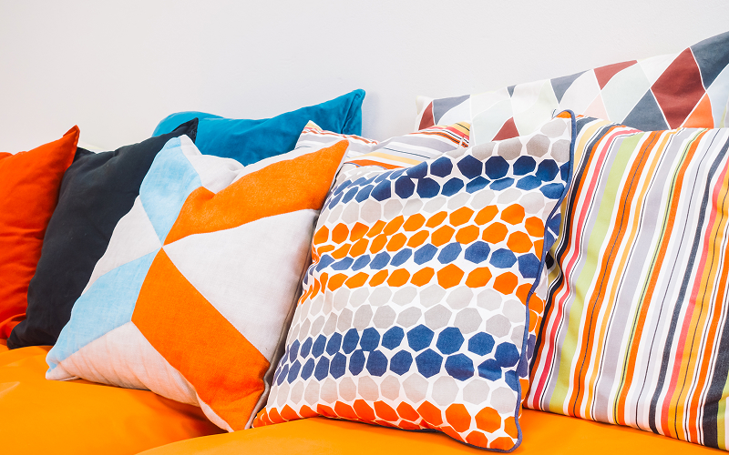 Image of a couch with many patterned cushions