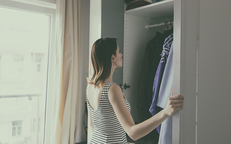 A backview image of a person looking into an open wardrobe.