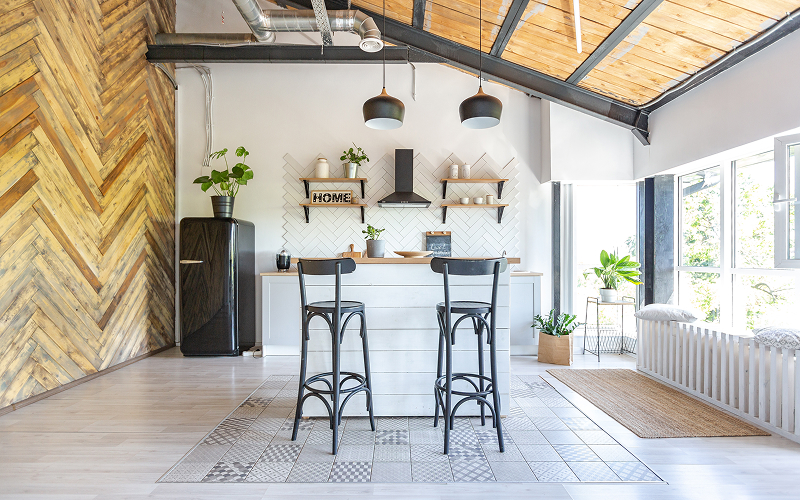 A kitchen and living space with exposed ductwork, metal-framed windows, and raw wooden dining furniture.