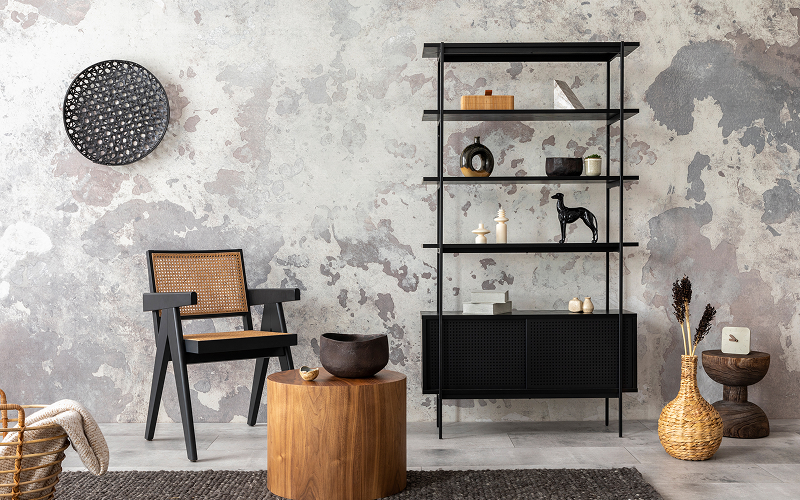 A loft-style living room with exposed brick, black metal shelving, and a concrete floor.
