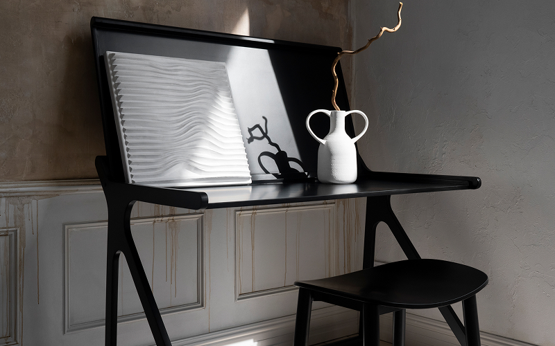 A raw cement wall finish paired with wooden furniture and black steel frames.