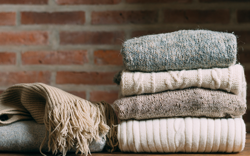 A stock photo of layered linens and a knitted throw.