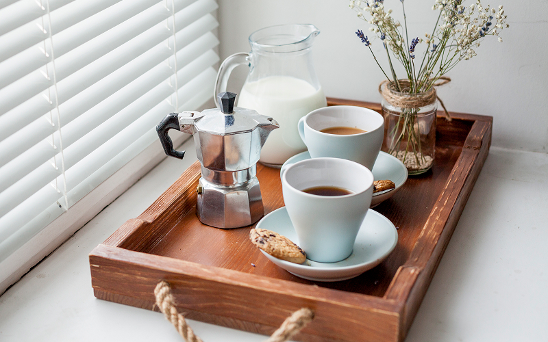 A bright kitchen scene with natural light streaming in, coffee mugs and breakfast items casually placed.