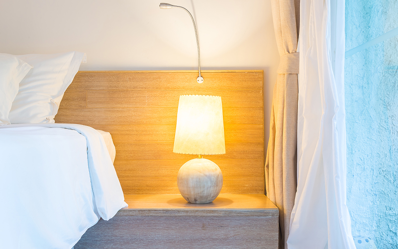 A stock photo of a calm bedroom with dimmable bedside lamps.