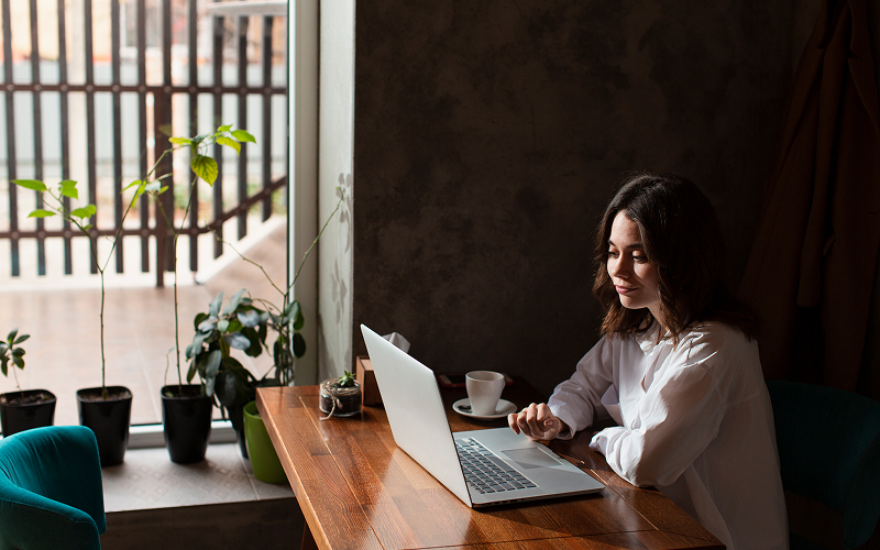 A young professional at a laptop in a study nook, with plants and soft lighting.