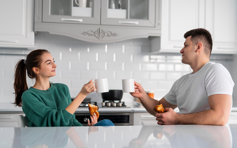 Two people sharing drinks at a kitchen counter top.