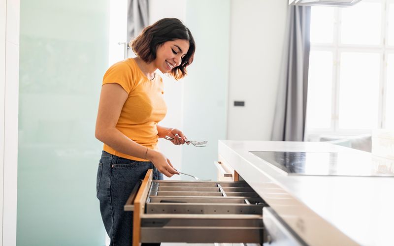 Image of a person storing things in a kitchen island cabinet